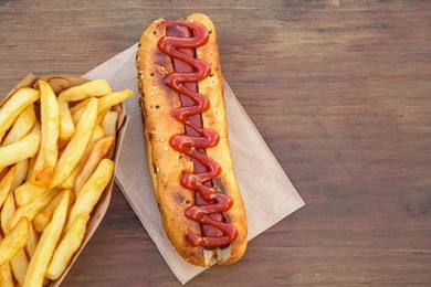 Photo of Fresh tasty hot dog and french fries on wooden table, flat lay. Space for text