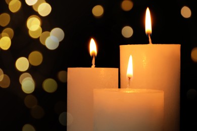 Burning candles on dark background with blurred lights. Bokeh effect