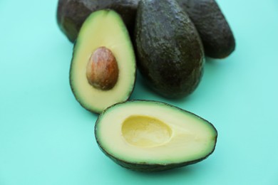 Photo of Tasty fresh ripe avocados on turquoise background