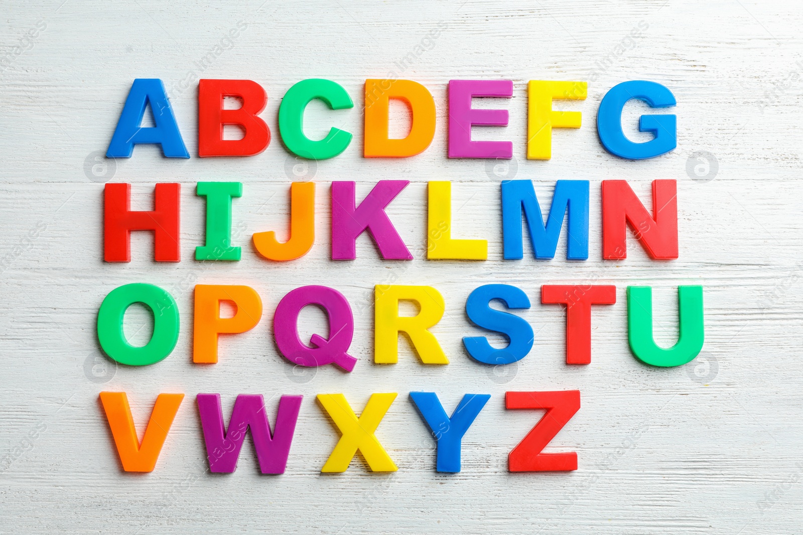 Photo of Plastic magnetic letters on wooden background, top view. Alphabetical order