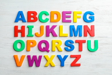 Photo of Plastic magnetic letters on wooden background, top view. Alphabetical order