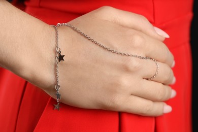 Photo of Woman wearing stylish metal chain with pendants and ring on her hand, closeup. Luxury jewelry