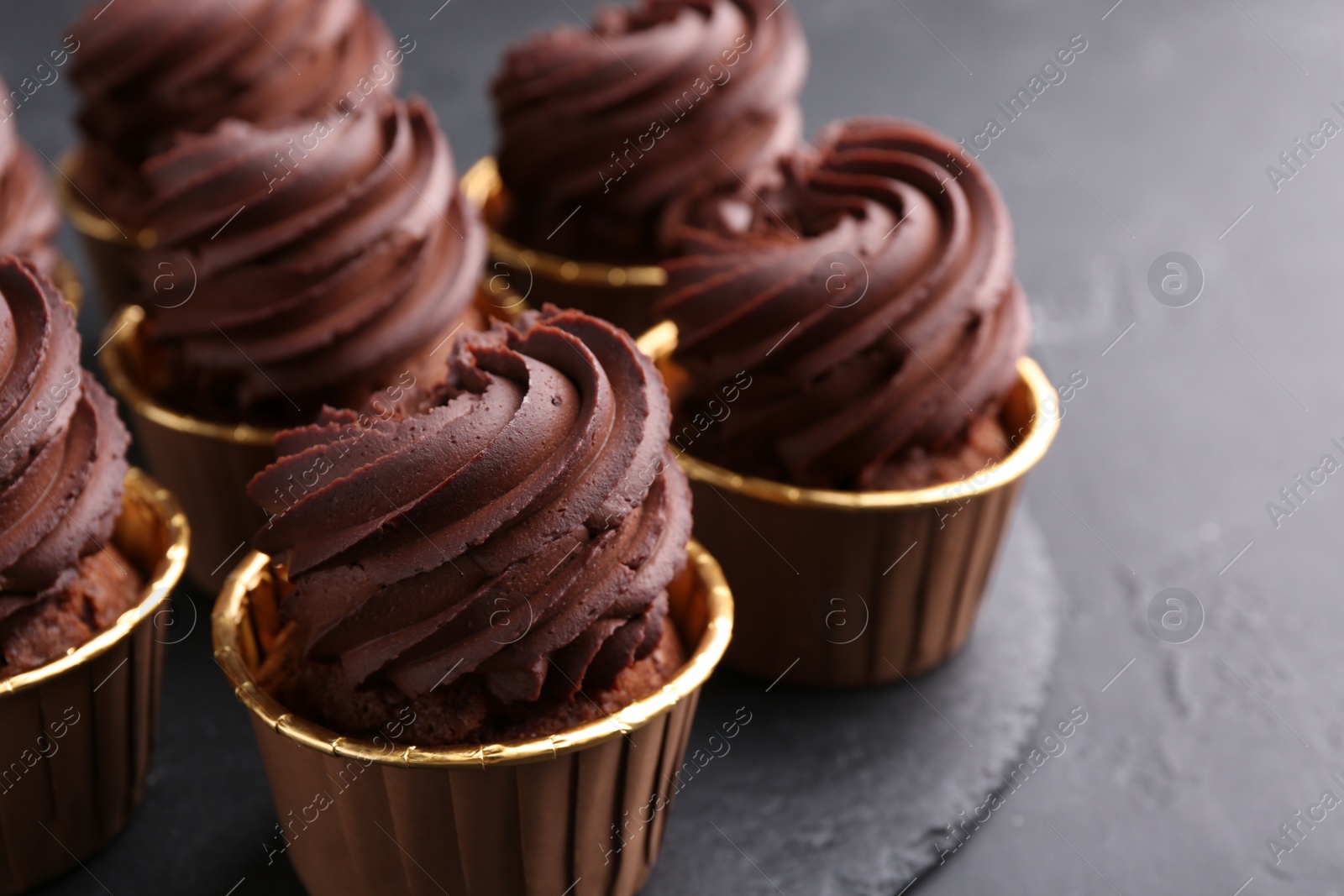 Photo of Delicious chocolate cupcakes on black table, closeup