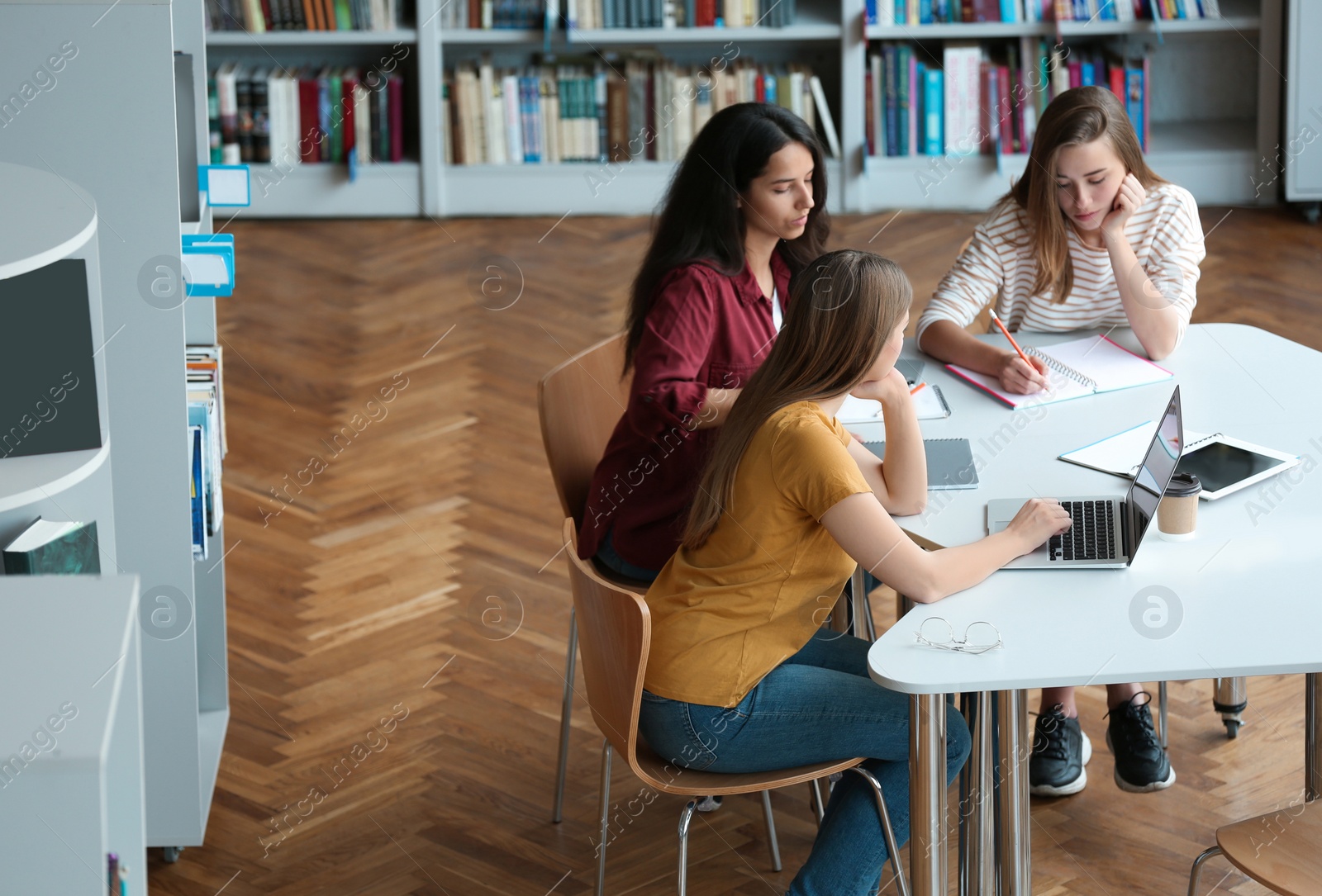 Photo of Young women discussing group project at table in library