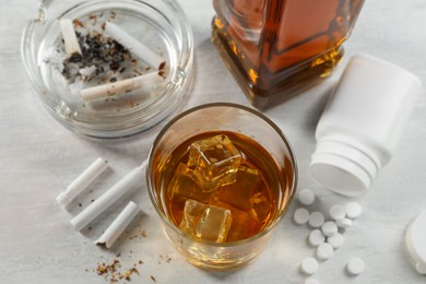 Photo of Alcohol and drug addiction. Whiskey in glass, cigarettes and pills on white table, above view