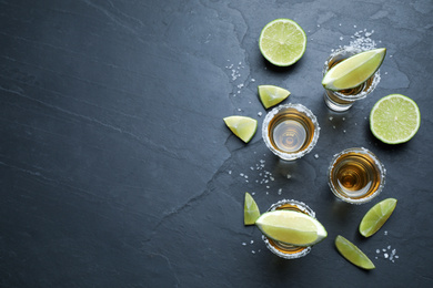 Photo of Mexican Tequila shots with salt and lime slices on grey table, flat lay. Space for text