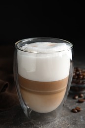 Photo of Delicious latte macchiato and coffee beans on grey table