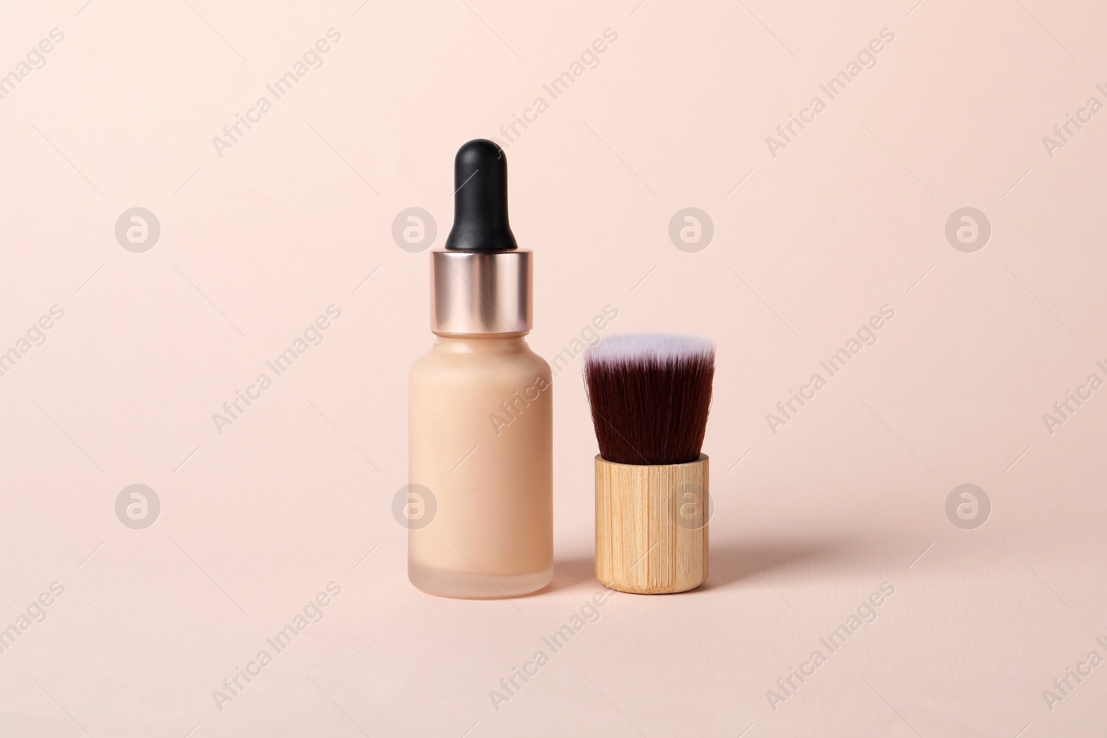 Photo of Bottle of skin foundation and brush on beige background. Makeup product