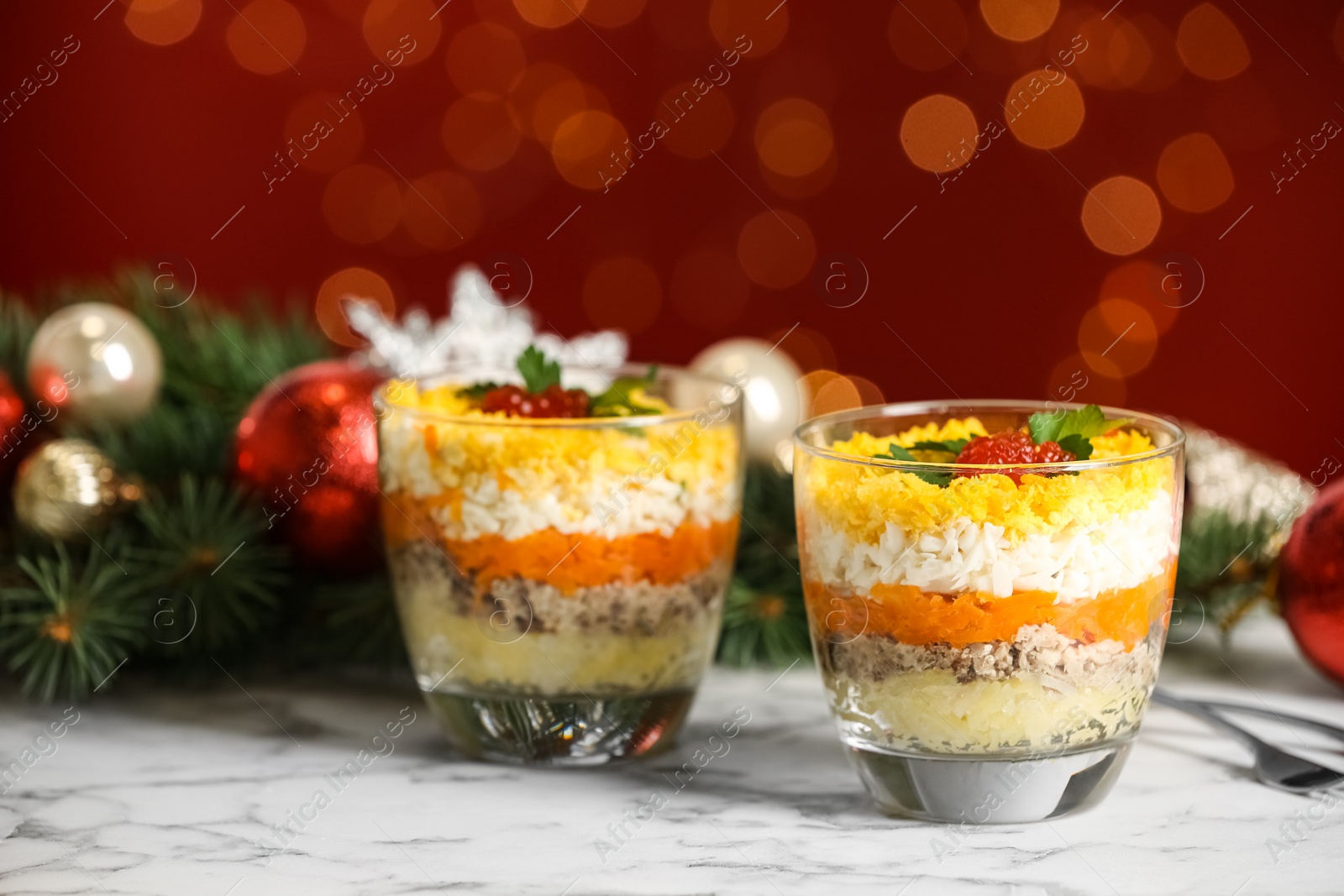 Photo of Traditional russian salad Mimosa and festive decor on table against blurred lights