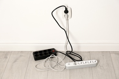 Extension cords with power plugs in socket indoors. Electrician's professional equipment