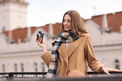 Photo of Beautiful woman in warm scarf with vintage camera outdoors