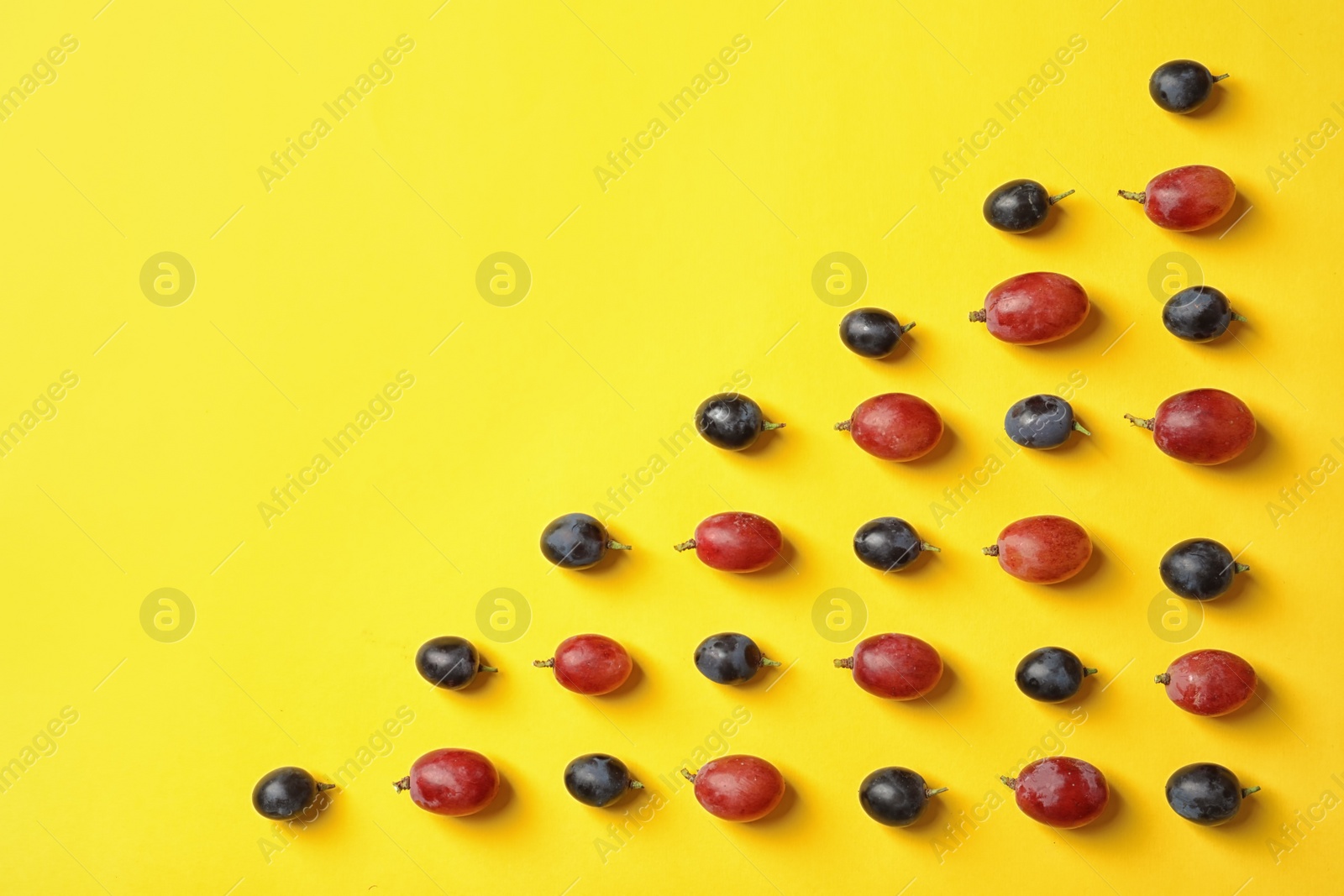 Photo of Fresh ripe juicy grapes on yellow background, top view. Space for text