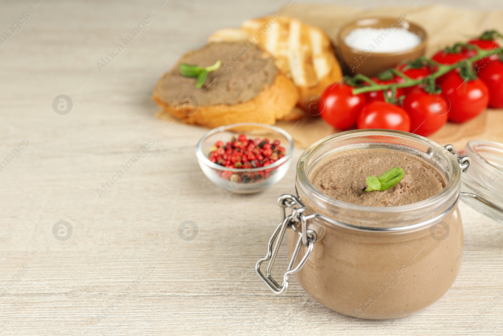 Photo of Glass jar with delicious liver pate on white wooden table, space for text