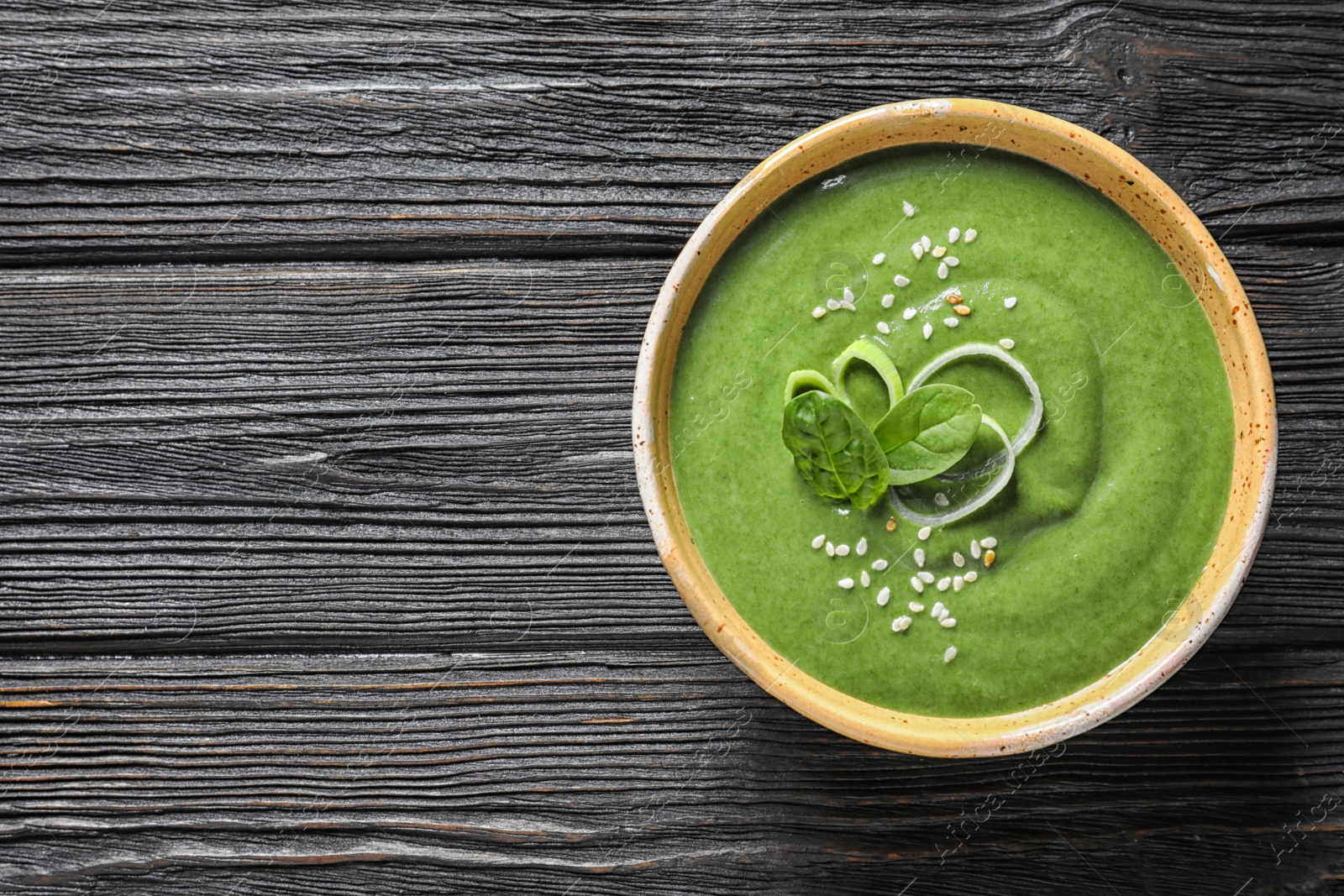 Photo of Fresh vegetable detox soup made of spinach in dish on wooden background, top view with space for text