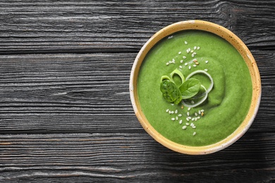 Photo of Fresh vegetable detox soup made of spinach in dish on wooden background, top view with space for text