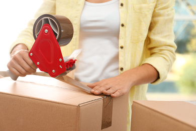 Photo of Woman packing box indoors, closeup. Moving day