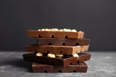 Photo of Delicious milk and dark chocolate bars with nuts on table