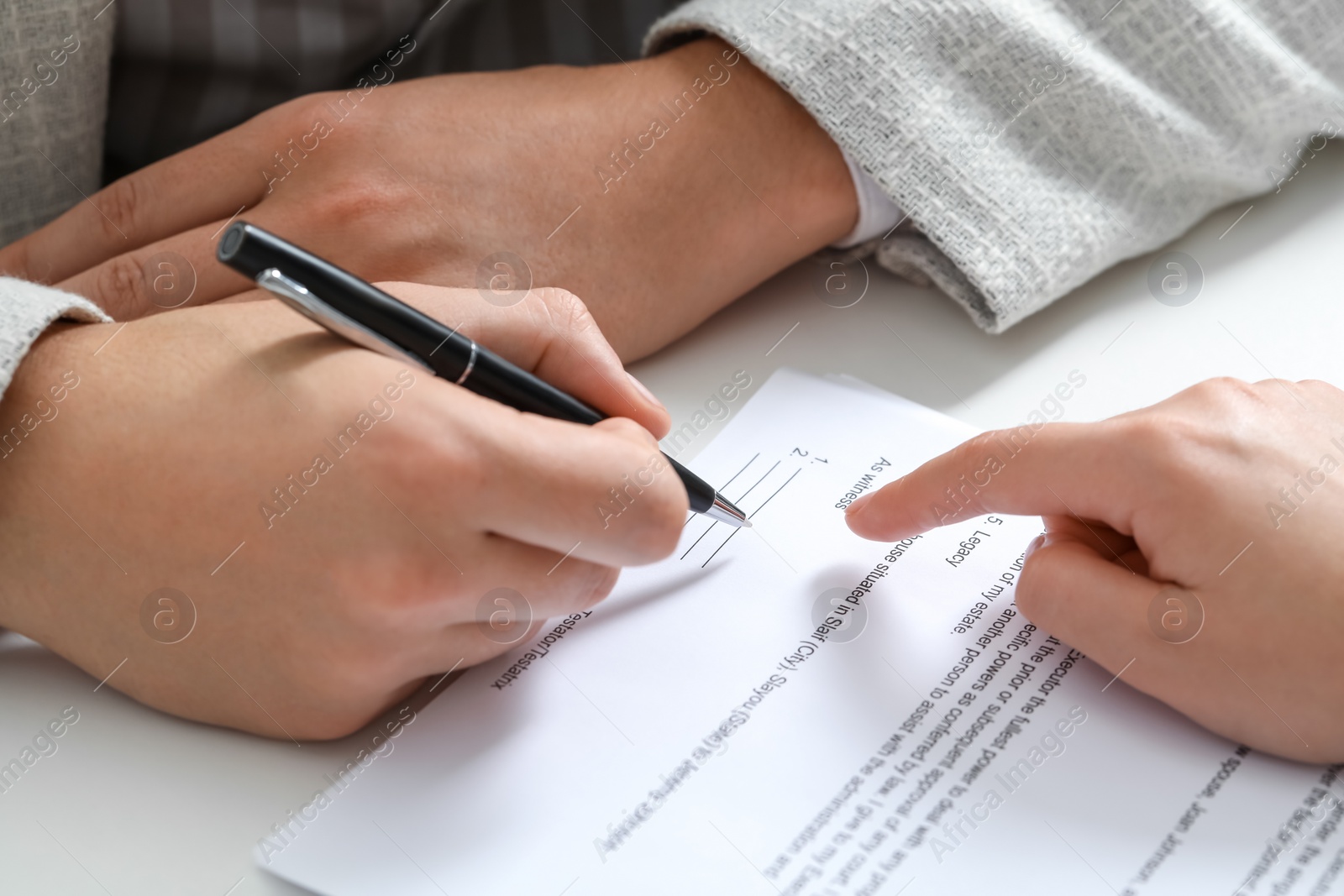 Photo of Woman pointing at document and man putting signature at white table, closeup