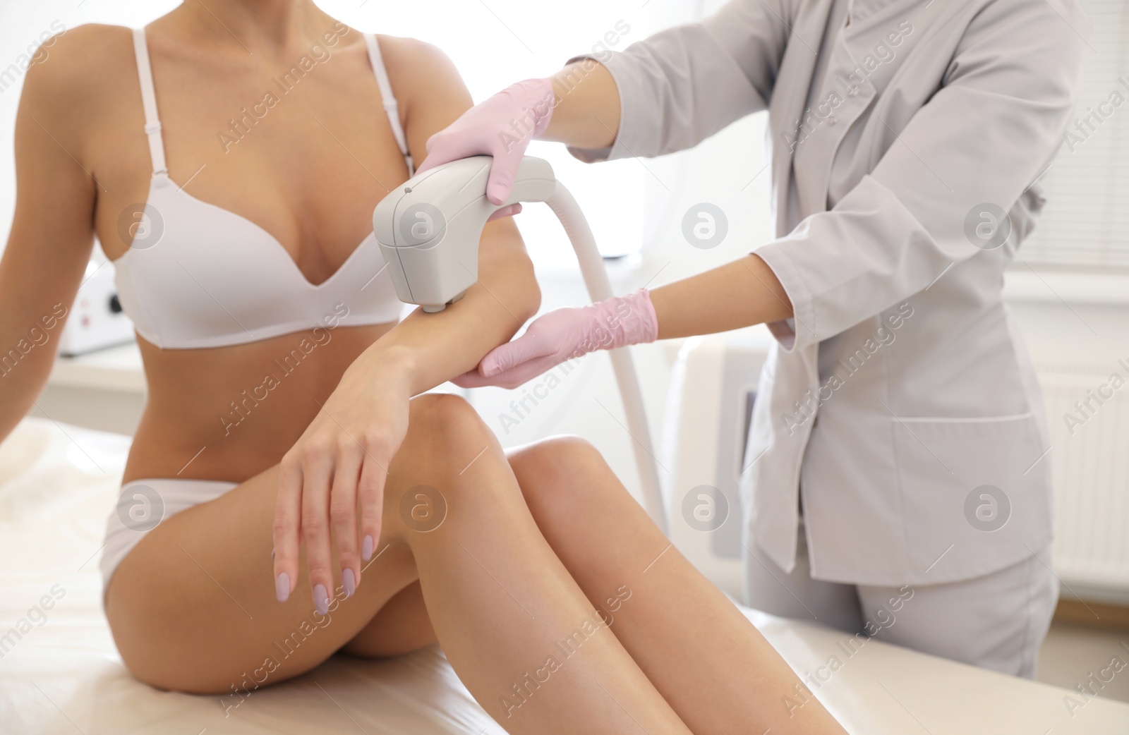 Photo of Young woman undergoing laser epilation procedure in beauty salon, closeup