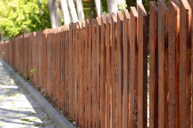 Photo of Wooden fence on sunny day near beautiful trees outdoors