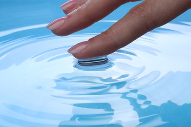 Woman touching clear water, closeup. Making ripples