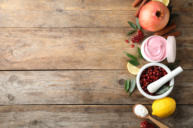 Flat lay composition with natural homemade mask, pomegranate and ingredients on wooden table. Space for text