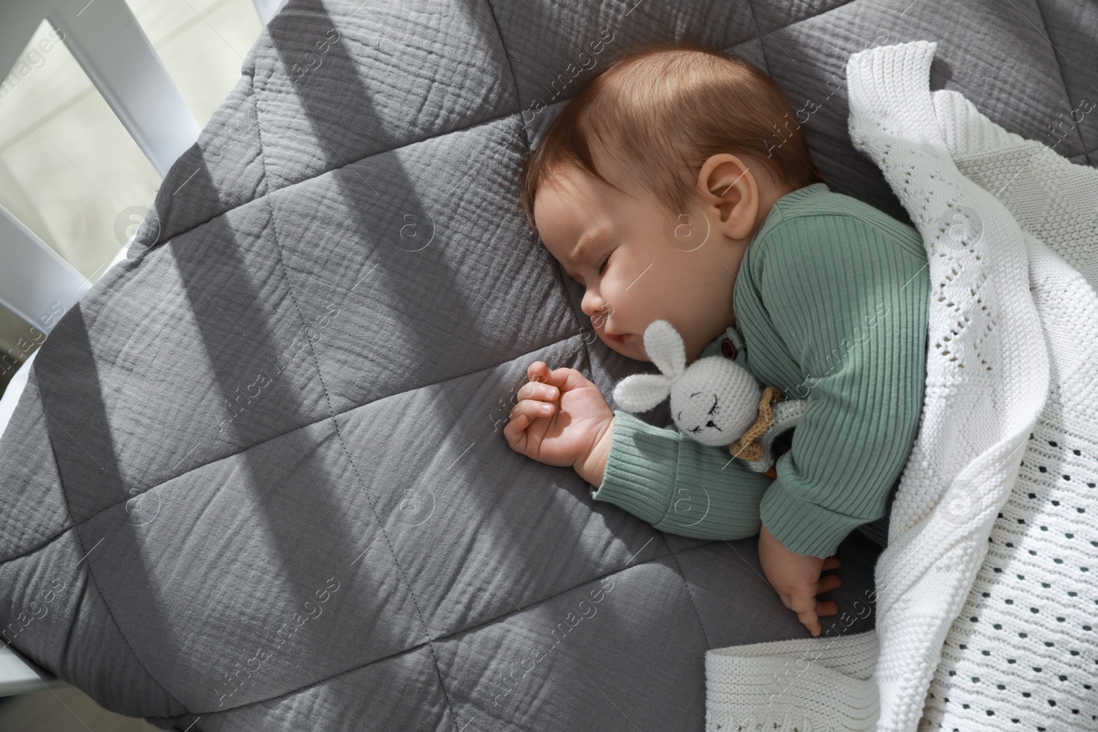 Photo of Cute little baby sleeping in crib, top view. Space for text