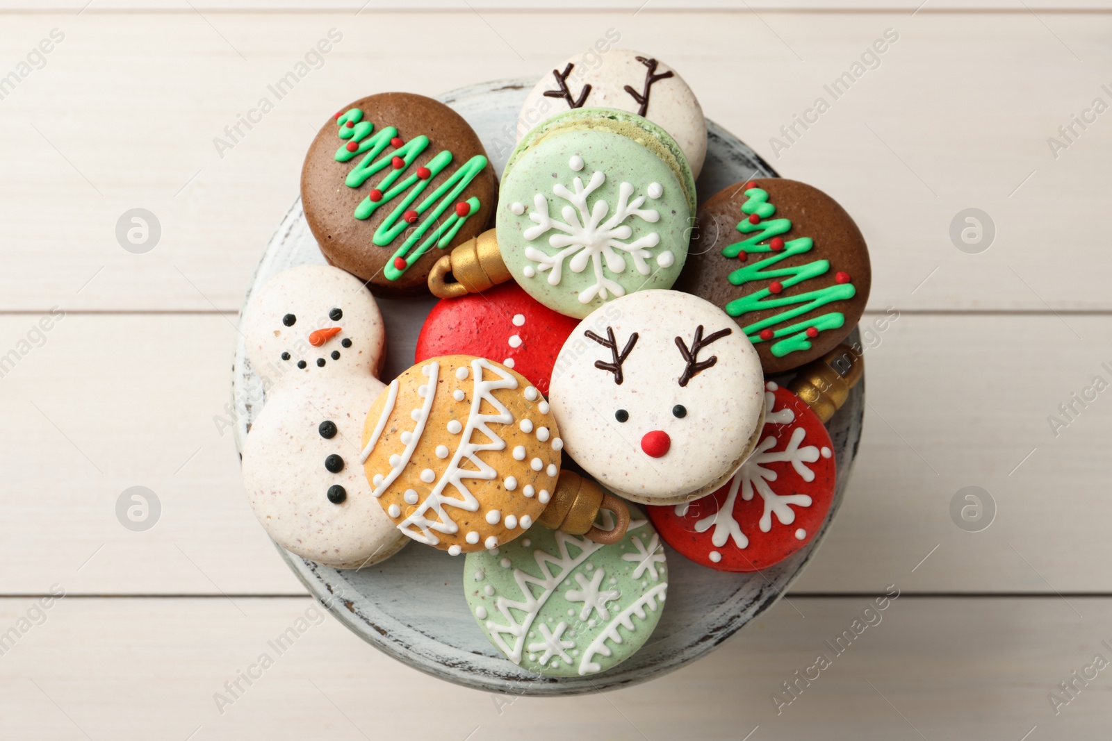 Photo of Beautifully decorated Christmas macarons on white wooden table, top view