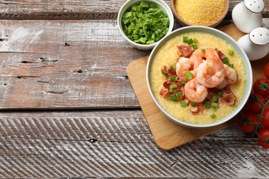 Photo of Fresh tasty shrimps, bacon, grits and green onion in bowl on wooden table, flat lay. Space for text