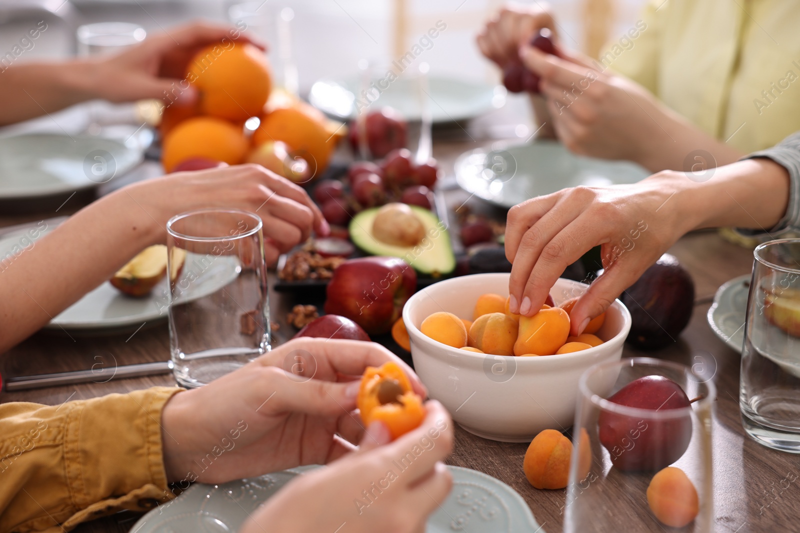 Photo of Vegetarian food. Friends eating fresh fruits at table indoors, closeup