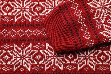 Photo of Warm Christmas sweater with snowflakes as background, closeup