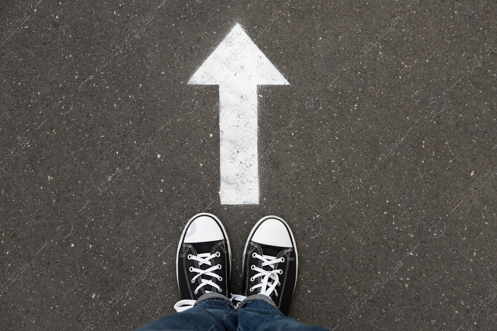 Photo of Woman standing near arrow on asphalt, top view. Choice concept