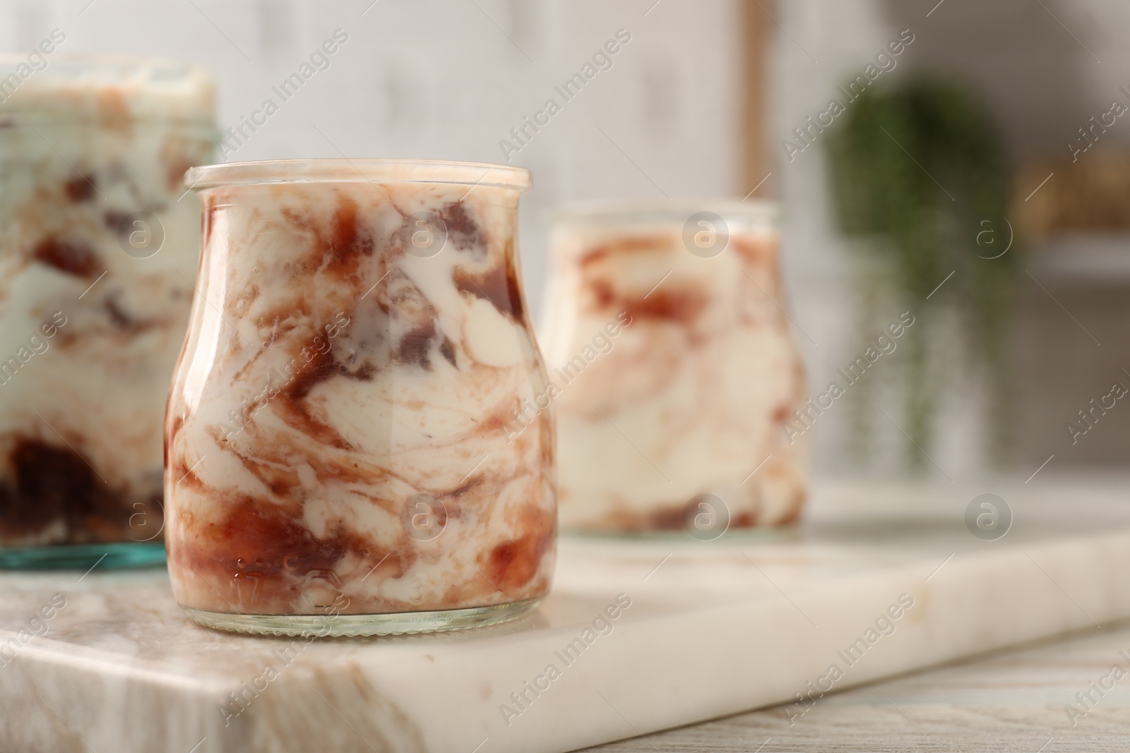 Photo of Tasty yoghurt with jam on white wooden table, closeup. Space for text