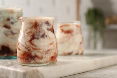 Photo of Tasty yoghurt with jam on white wooden table, closeup. Space for text