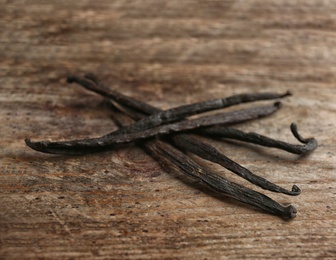 Photo of Bunch of vanilla sticks on wooden background, closeup