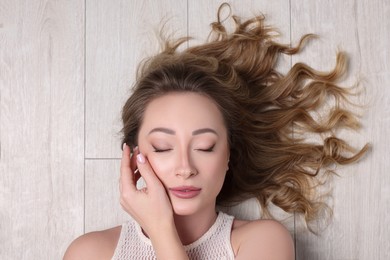 Photo of Portrait of beautiful woman with closed eyes on wooden floor, top view