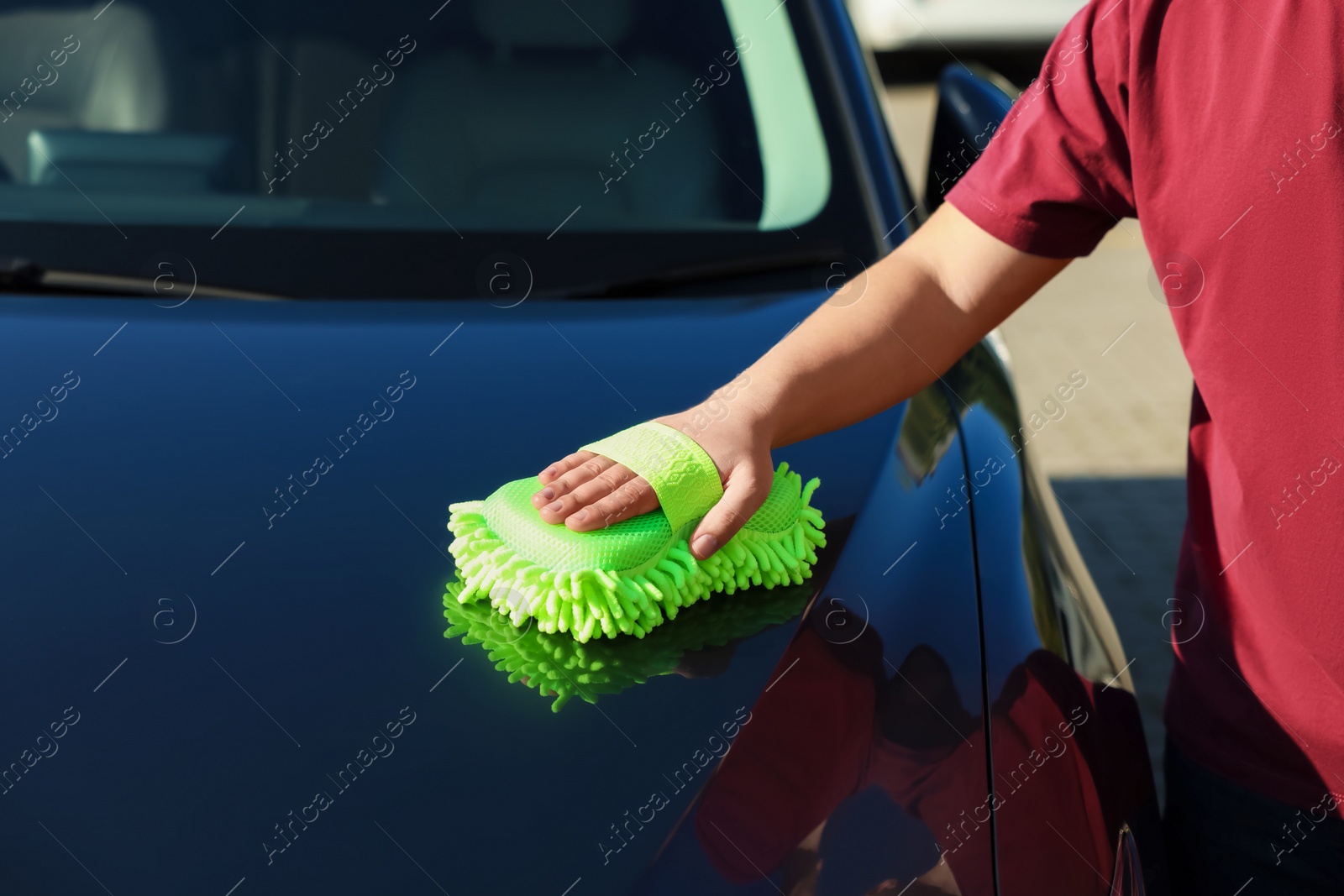 Photo of Man cleaning car hood outdoors, closeup view