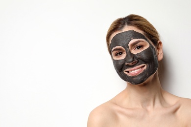 Beautiful woman with black mask on face against light background. Space for text