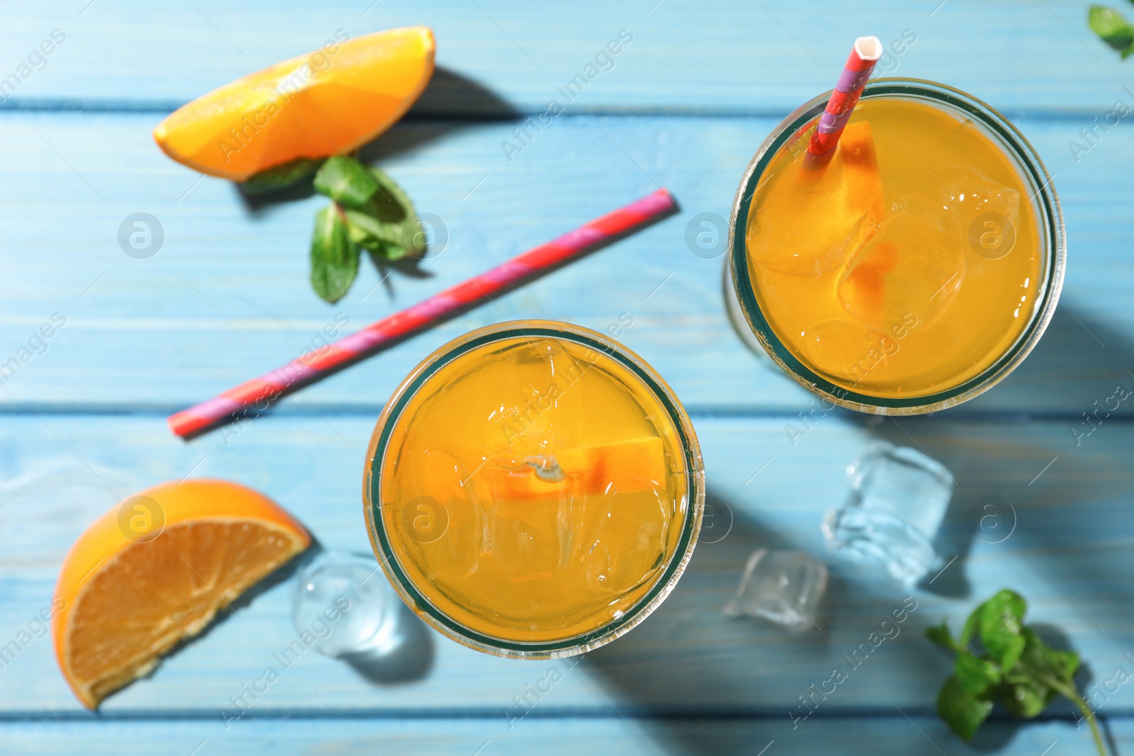 Photo of Delicious orange soda water on light blue wooden table, flat lay