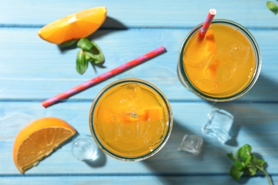 Delicious orange soda water on light blue wooden table, flat lay