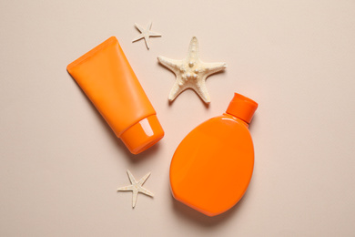 Photo of Sun protection products and starfishes on beige background, flat lay