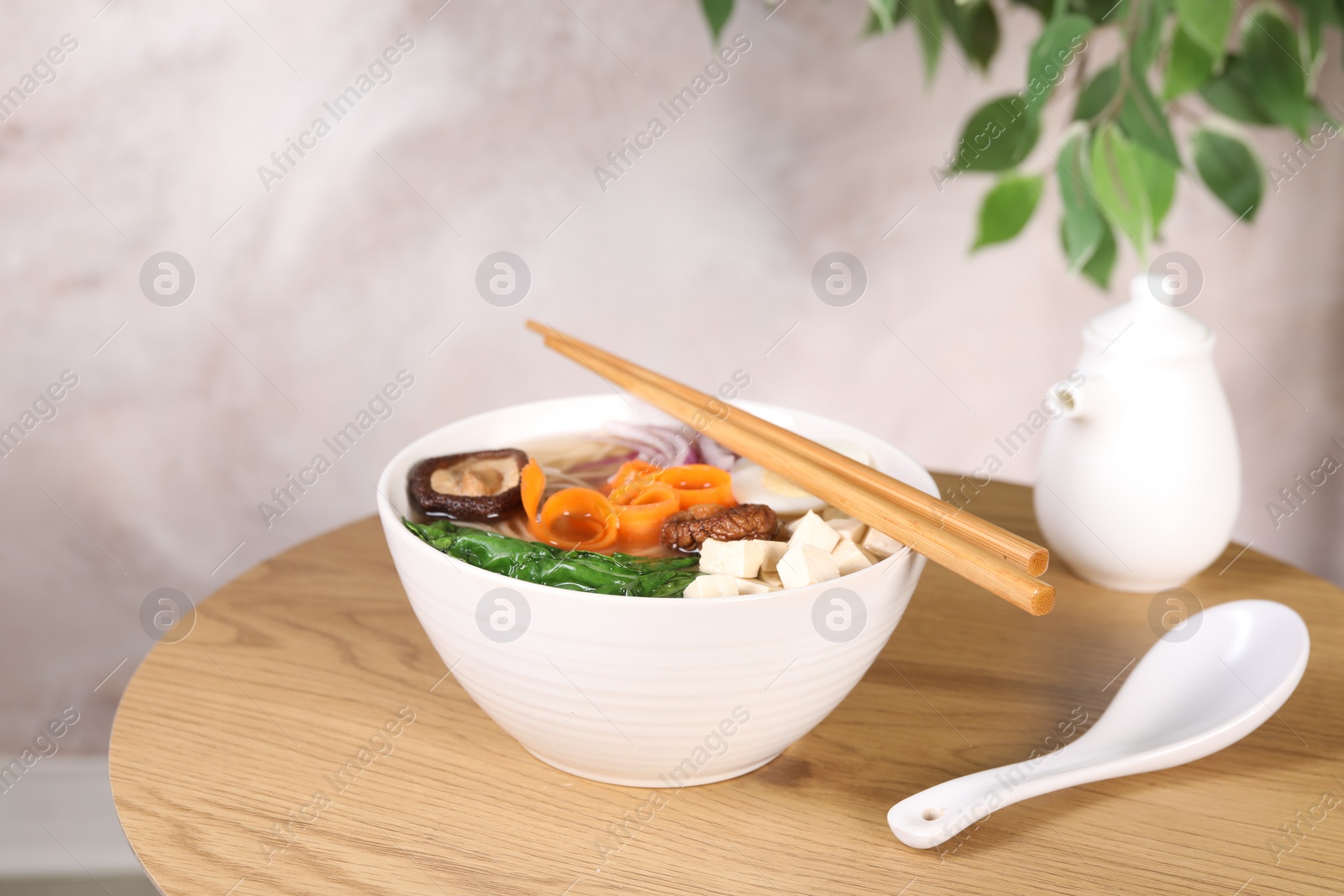 Photo of Delicious vegetarian ramen served on wooden table. Noodle soup