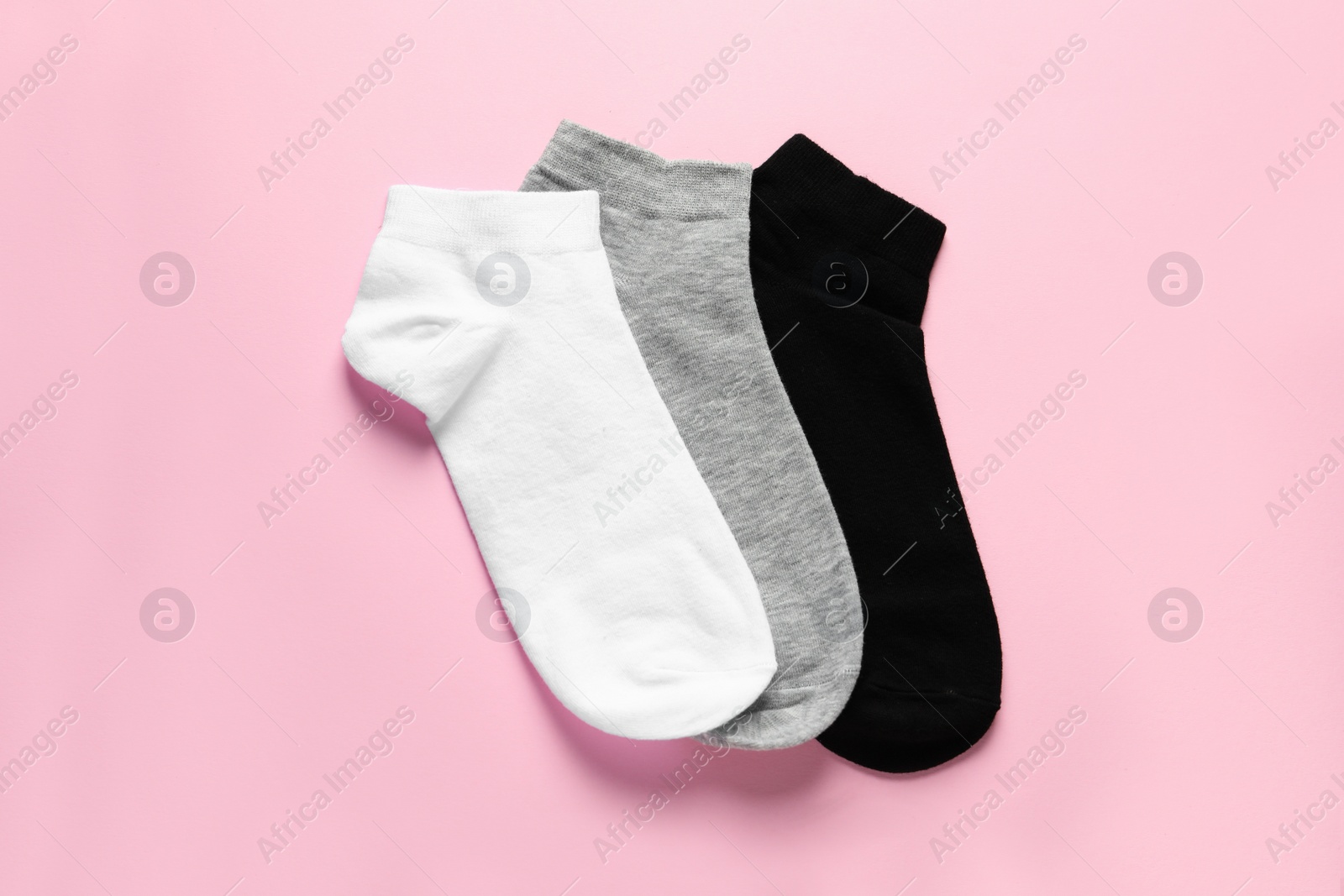 Photo of Different socks on pink background, flat lay