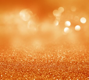 Shiny orange glitter and blurred lights on background. Bokeh effect