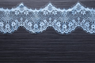 Photo of Light blue lace on black table, top view. Space for text