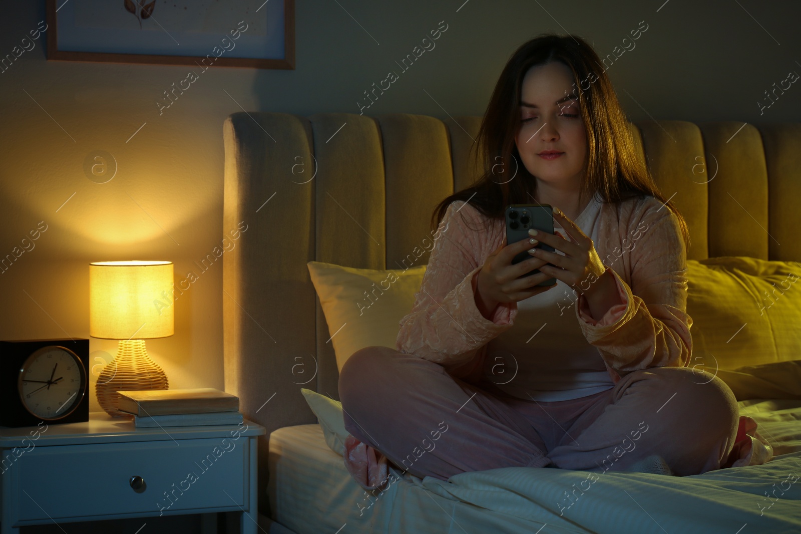 Photo of Woman using smartphone on bed at night. Internet addiction