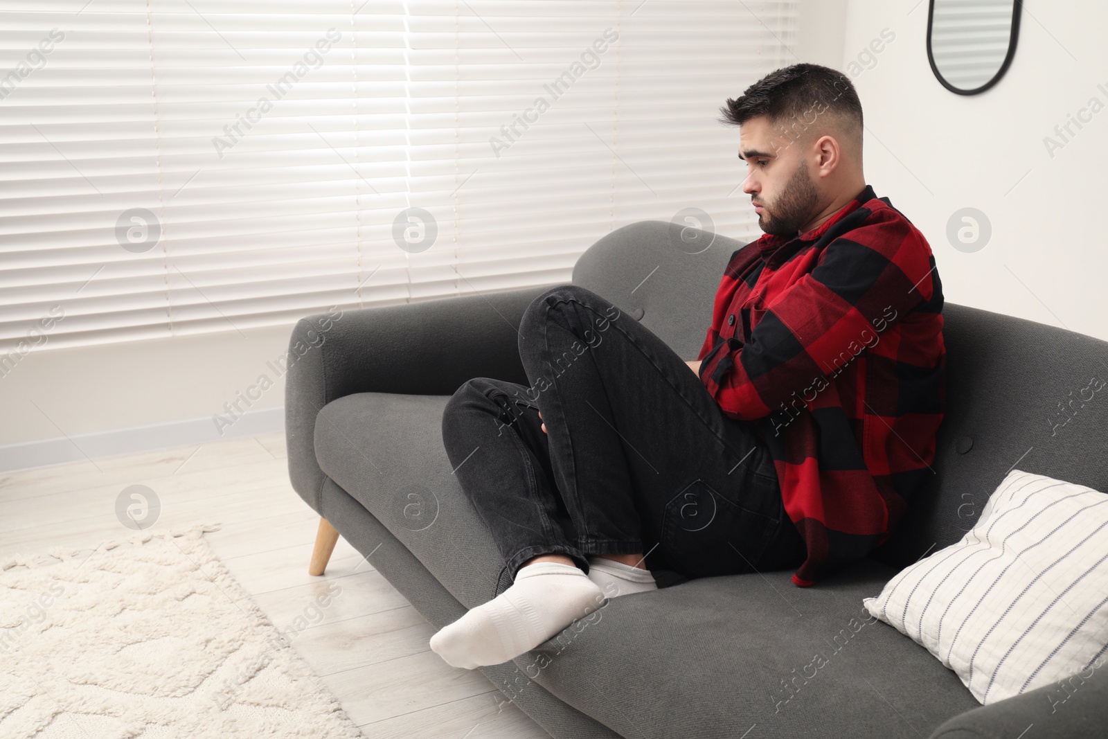 Photo of Sad lonely man on sofa at home. Space for text