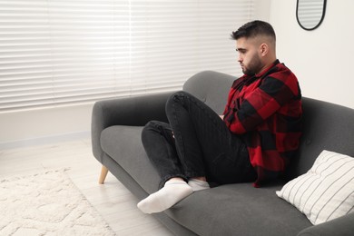 Photo of Sad lonely man on sofa at home. Space for text