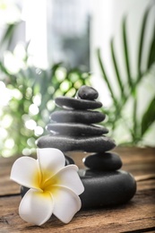 Photo of Table with stack of stones, flower and blurred green leaves on background. Zen concept