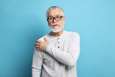Photo of Arthritis symptoms. Man suffering from pain in shoulder on light blue background